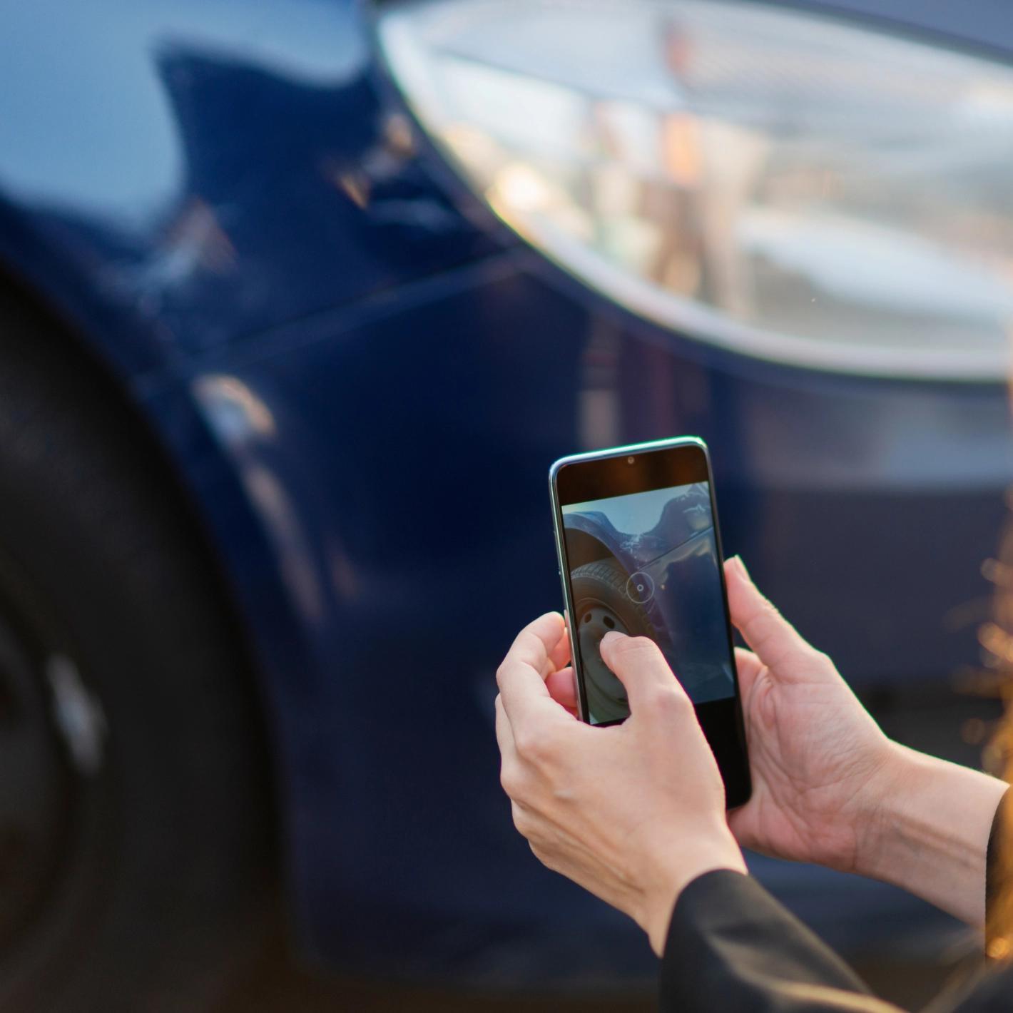 Dettaglio di una persona che fotografa il danno della propria auto con uno smartphone: i nostri servizi sono sempre a portata di mano.